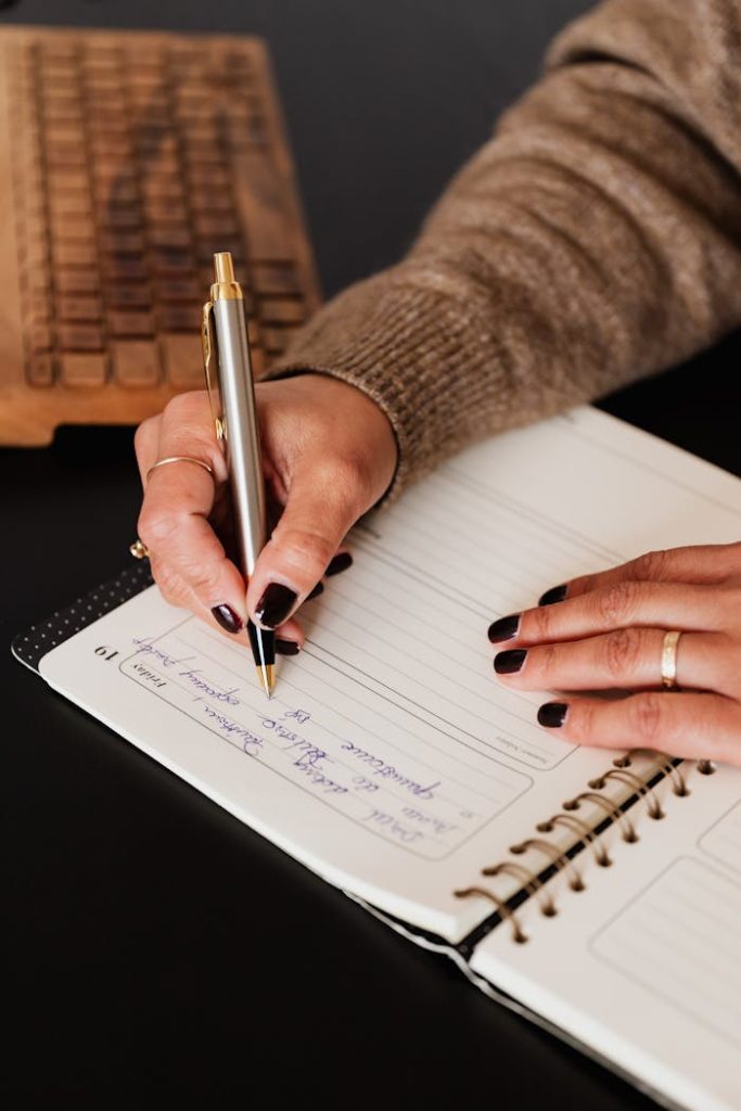 Crop woman writing notes in notebook